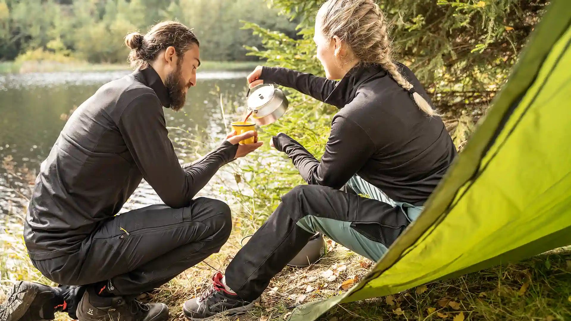 Mand og kvinde drikker kaffe ved sø 