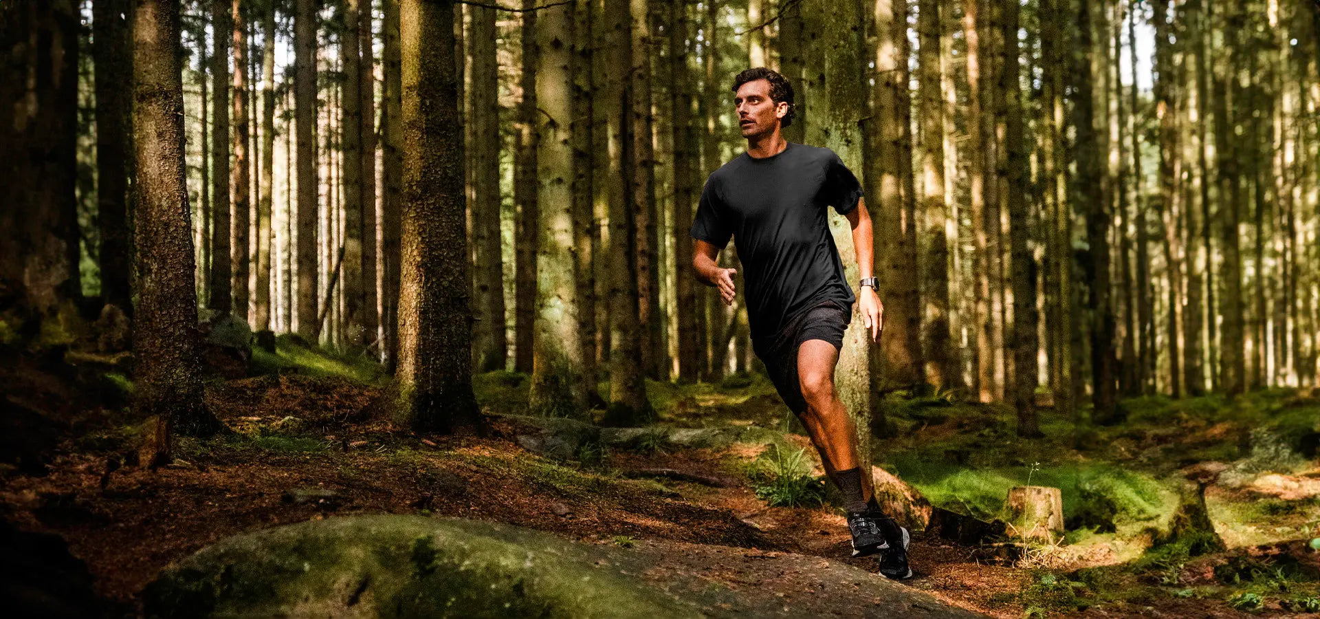 Mand løber gennem skoven i en sort t-shirt